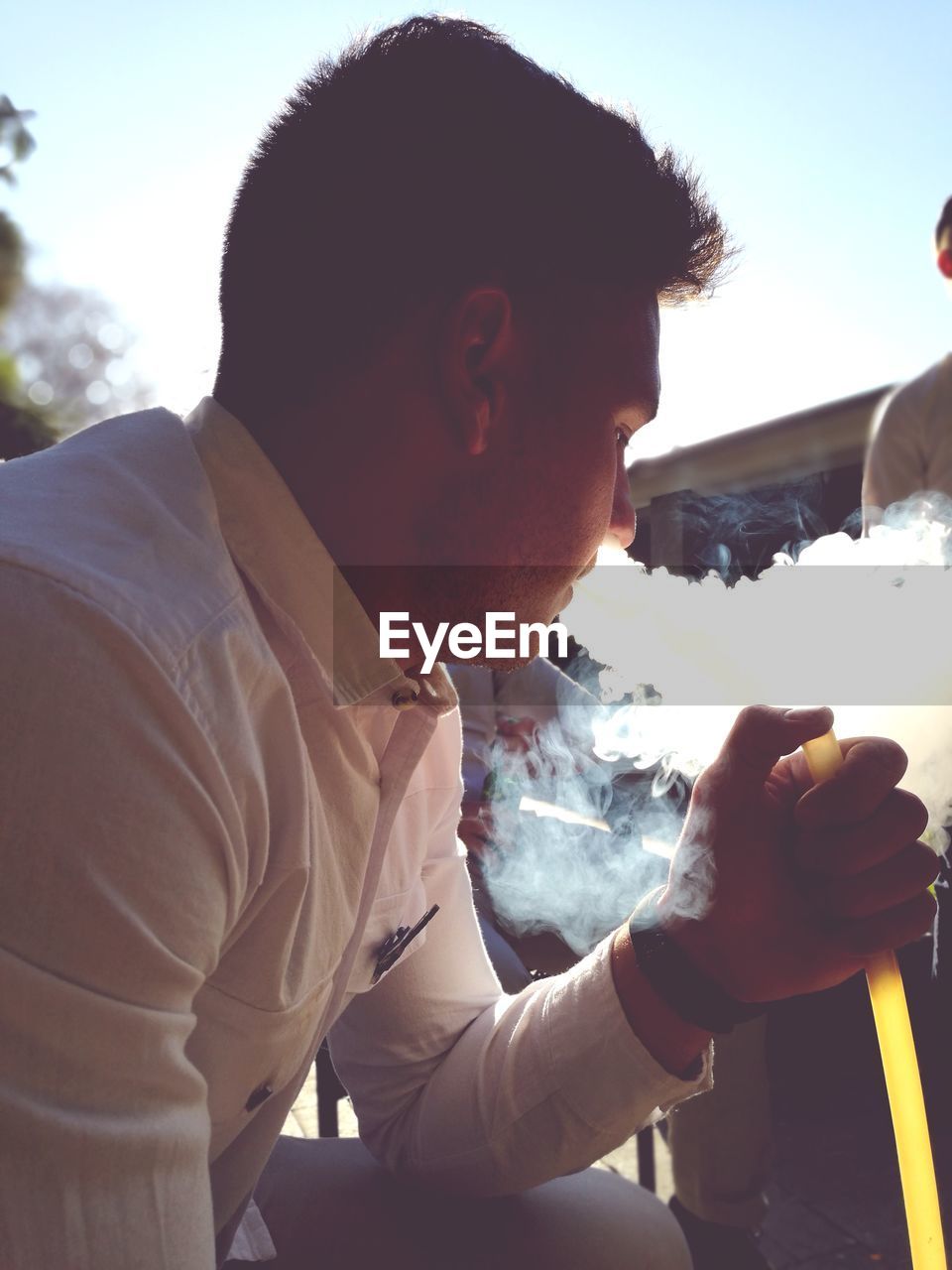 Young man smoking hookah against sky