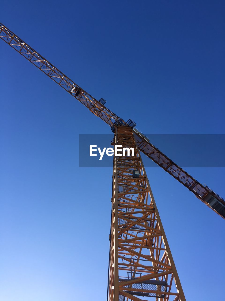 Low angle view of crane against clear blue sky