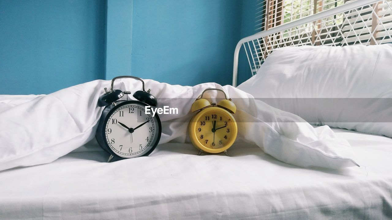 Alarm clocks on bed at home