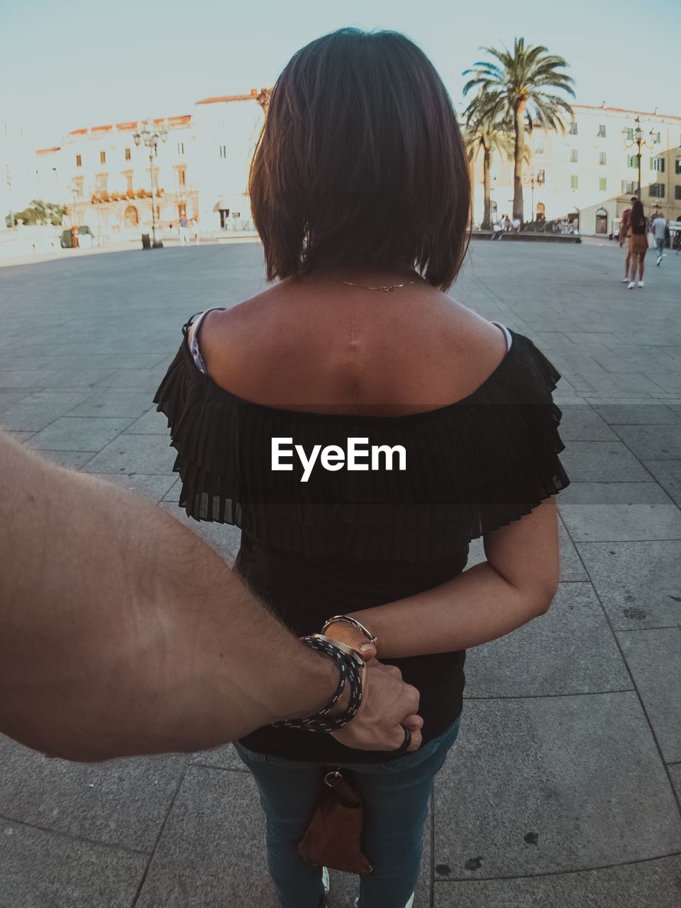 REAR VIEW OF COUPLE STANDING ON STREET