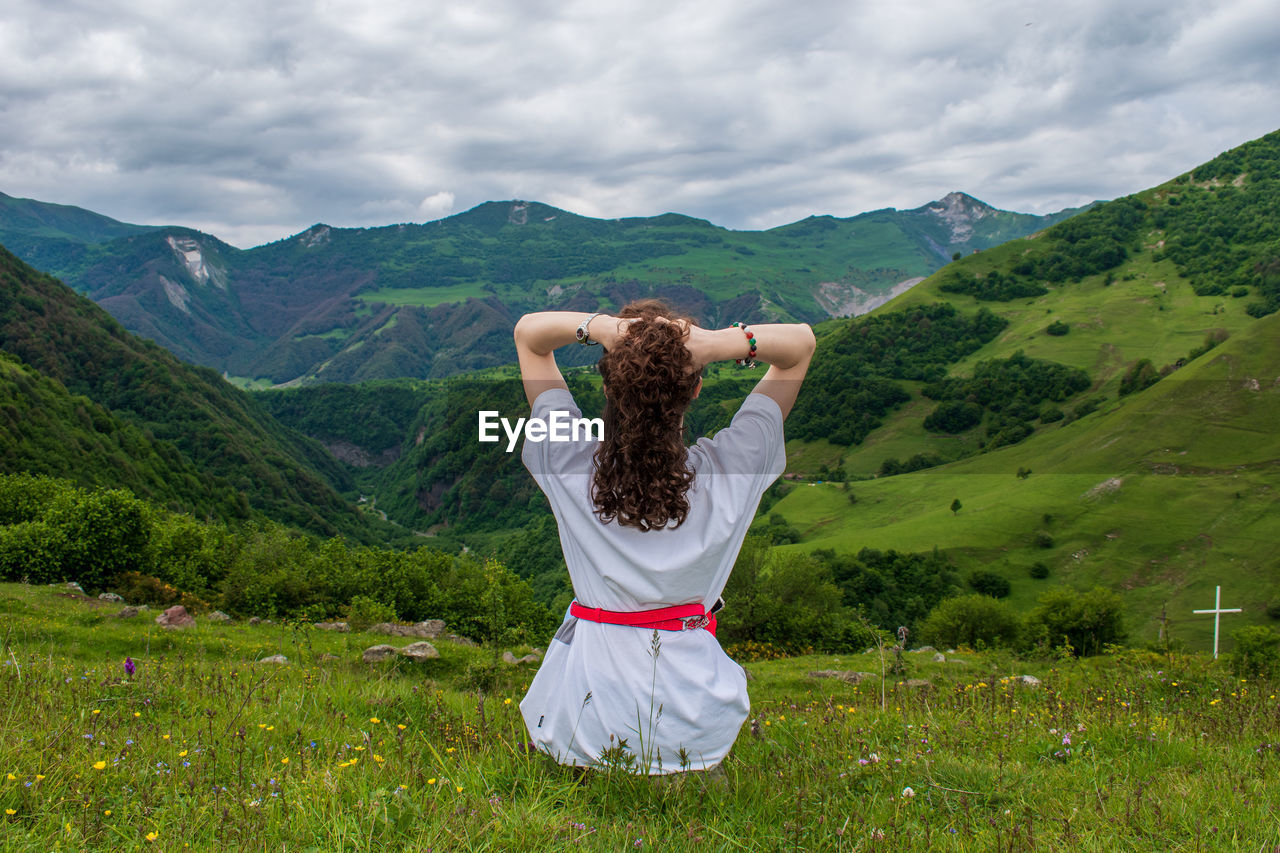 Rear view of man standing on landscape against mountain range