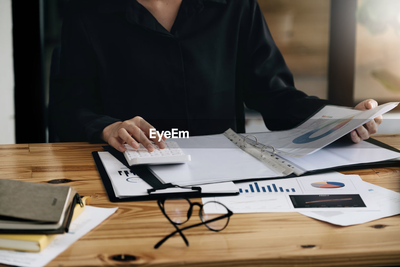 Midsection of businesswoman working on table