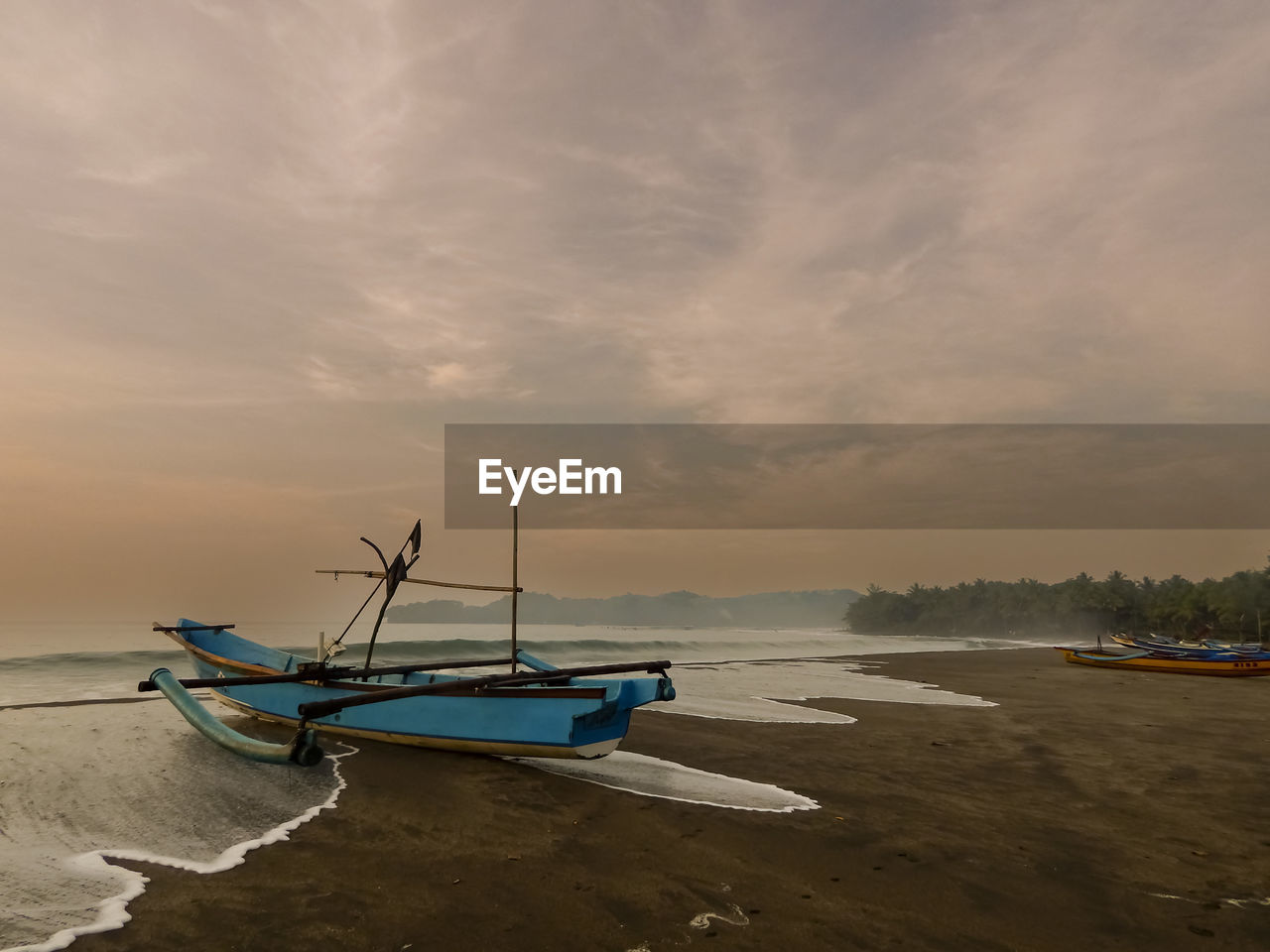 Boat moored on shore against sky during sunrise