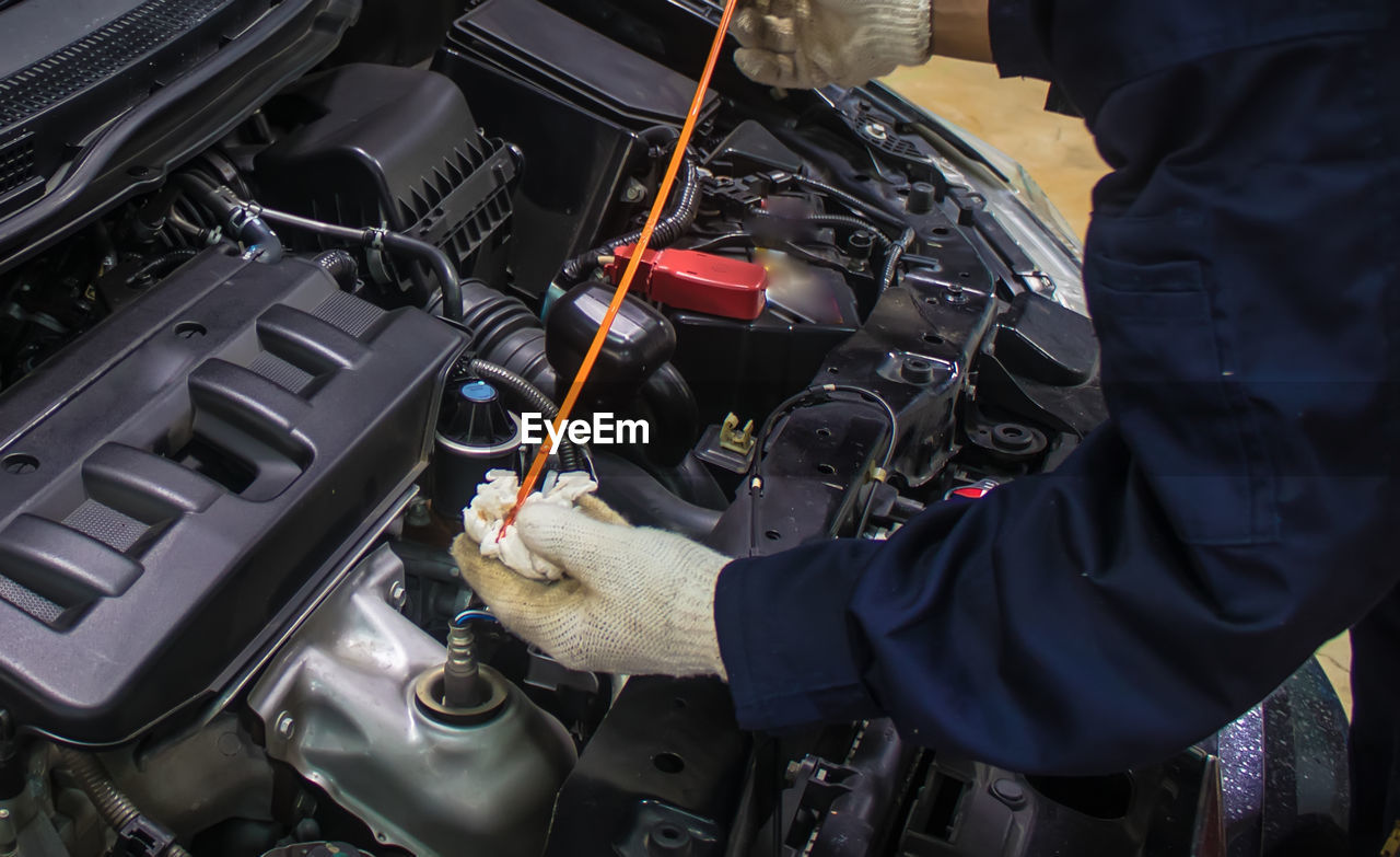 Cropped hands of mechanic repairing in car