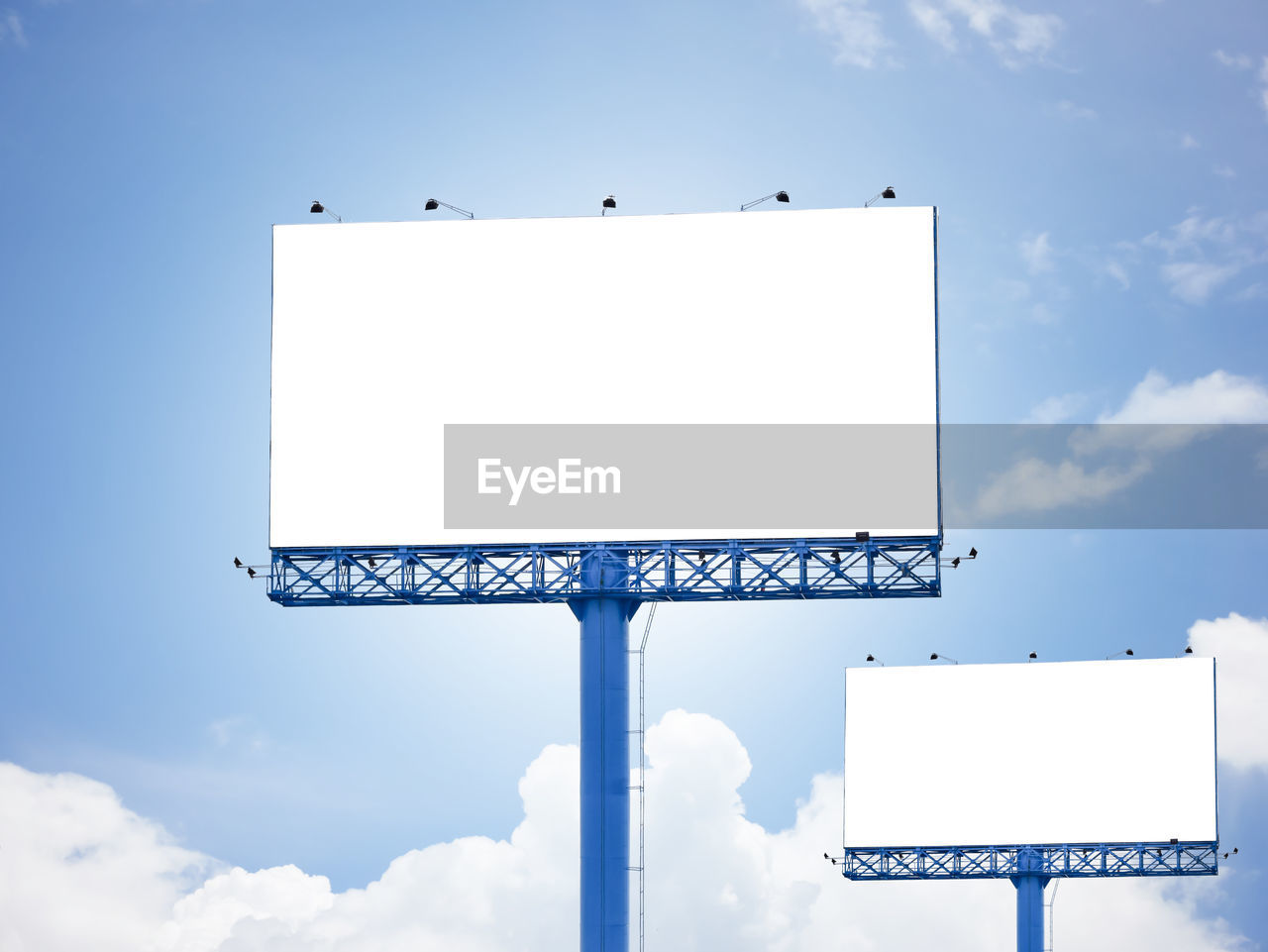 Low angle view of blank billboards against blue sky