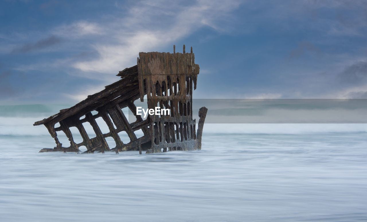 Wreck of the peter iredale in sea against sky
