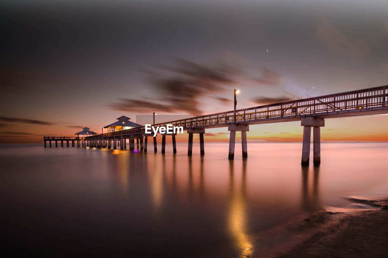 Bridge over sea against sky during sunset