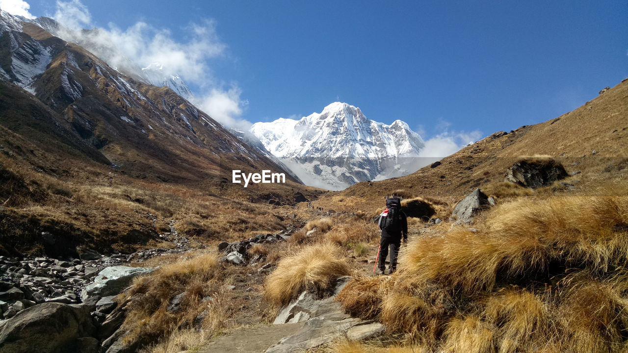 Man walking on snowcapped mountain against sky