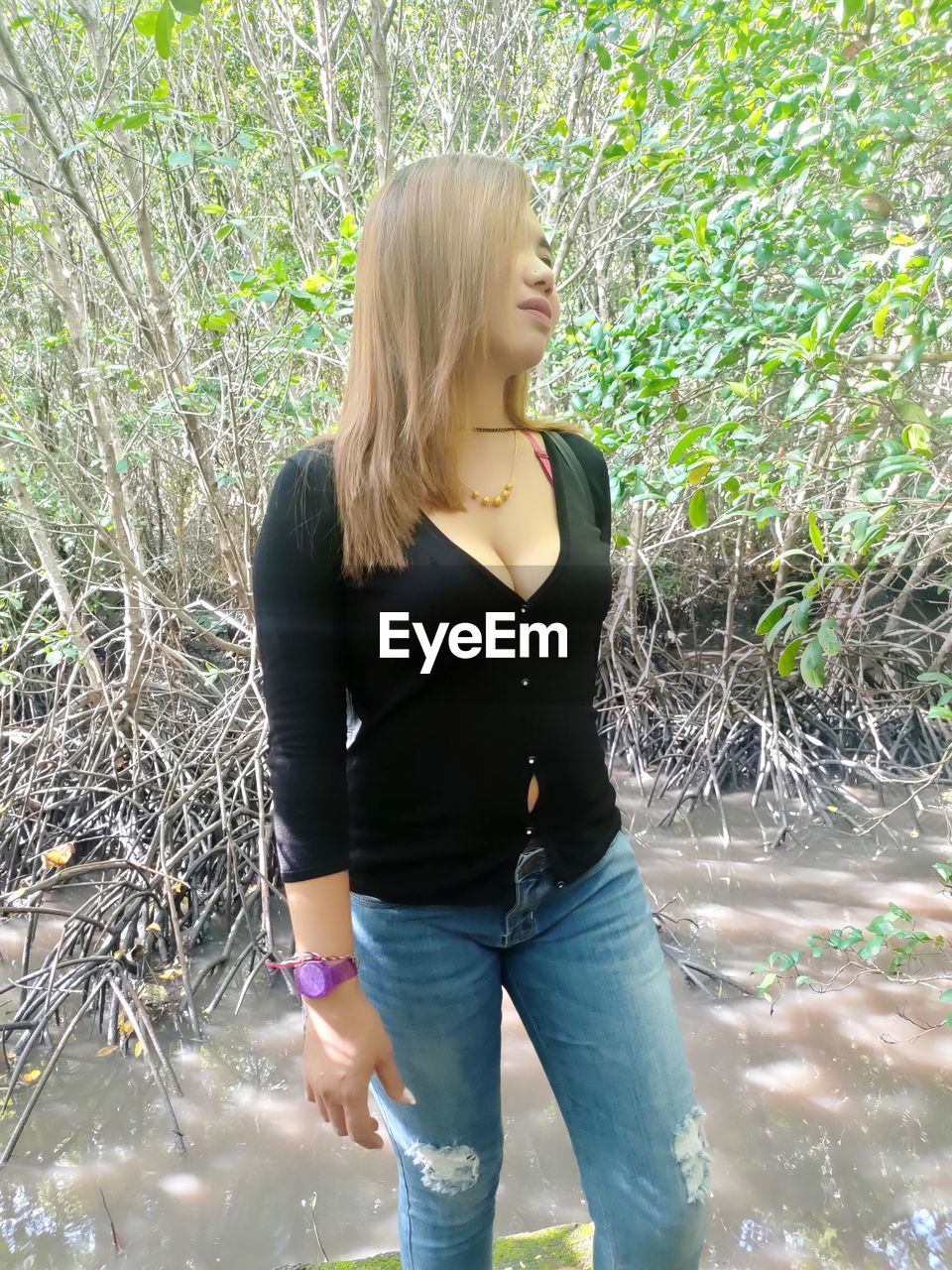 FULL LENGTH OF WOMAN STANDING IN FRONT OF PLANTS