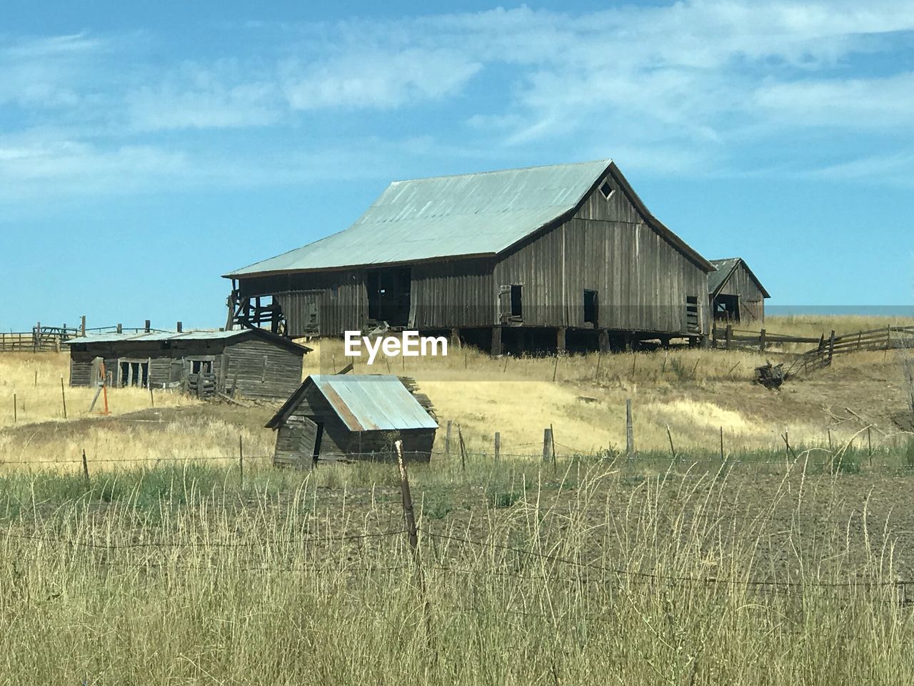 ABANDONED BARN ON FIELD AGAINST BUILDINGS