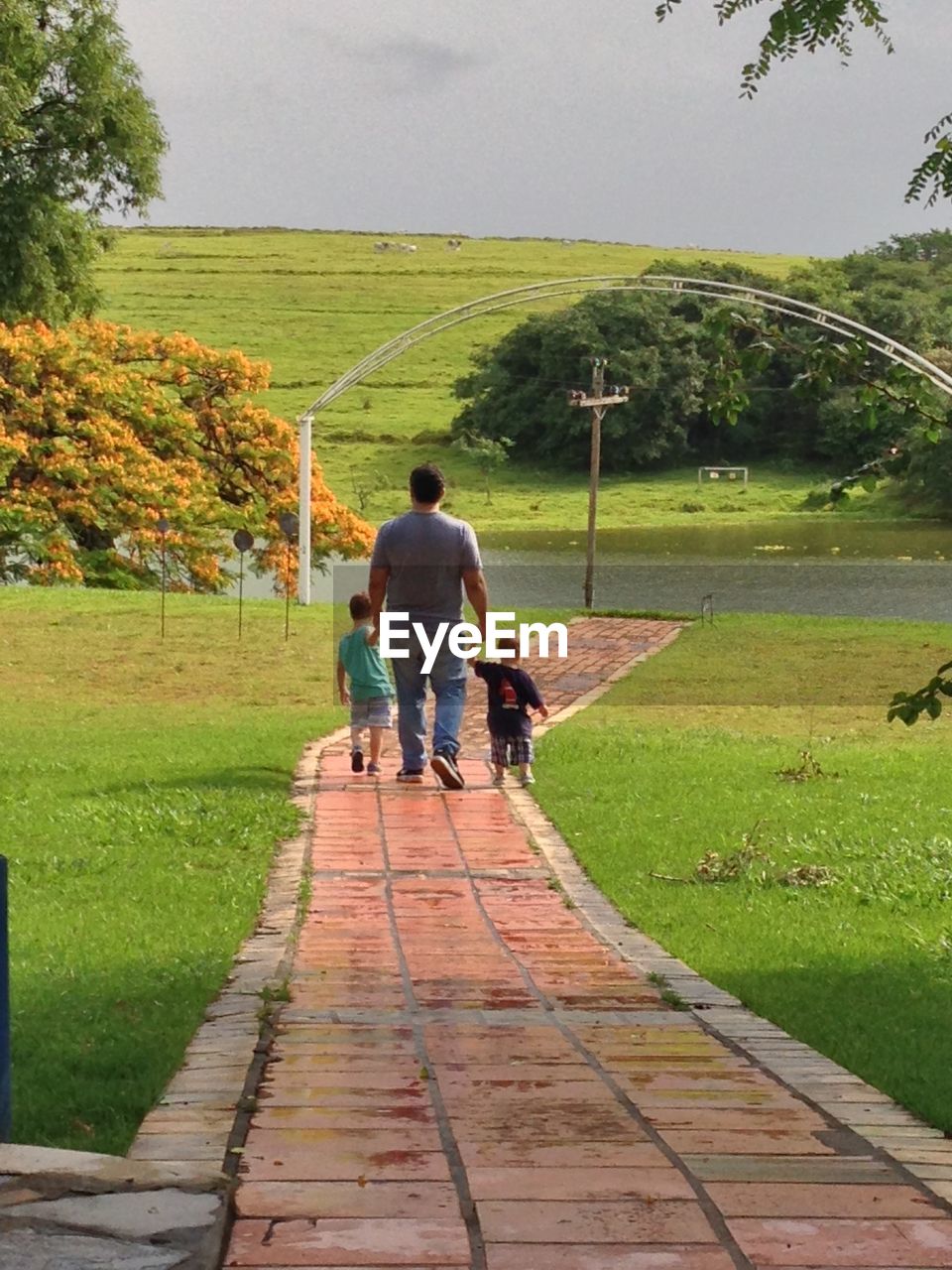 REAR VIEW OF MOTHER AND SON WALKING ON FOOTPATH