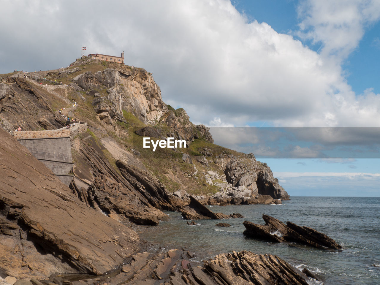 Scenic view of sea by mountain against sky in the spanish island of gaztelugatxe