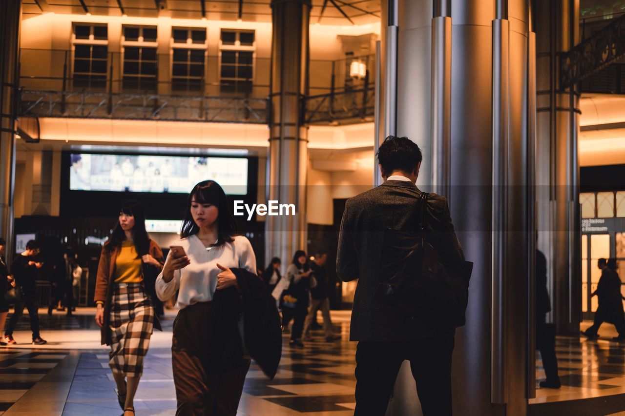 GROUP OF PEOPLE WALKING IN CORRIDOR ALONG BUILDING