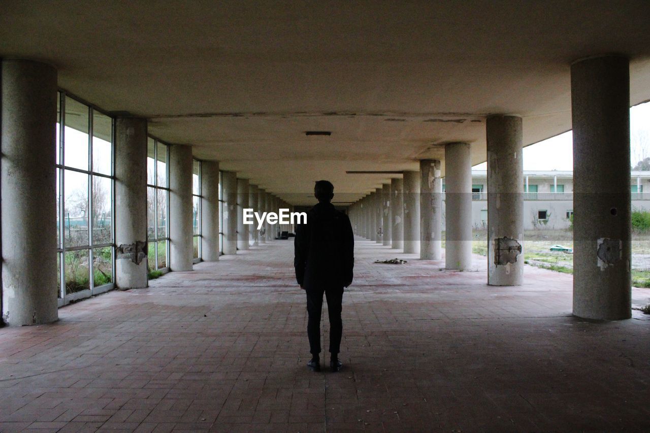 Silhouette man standing walkway under bridge