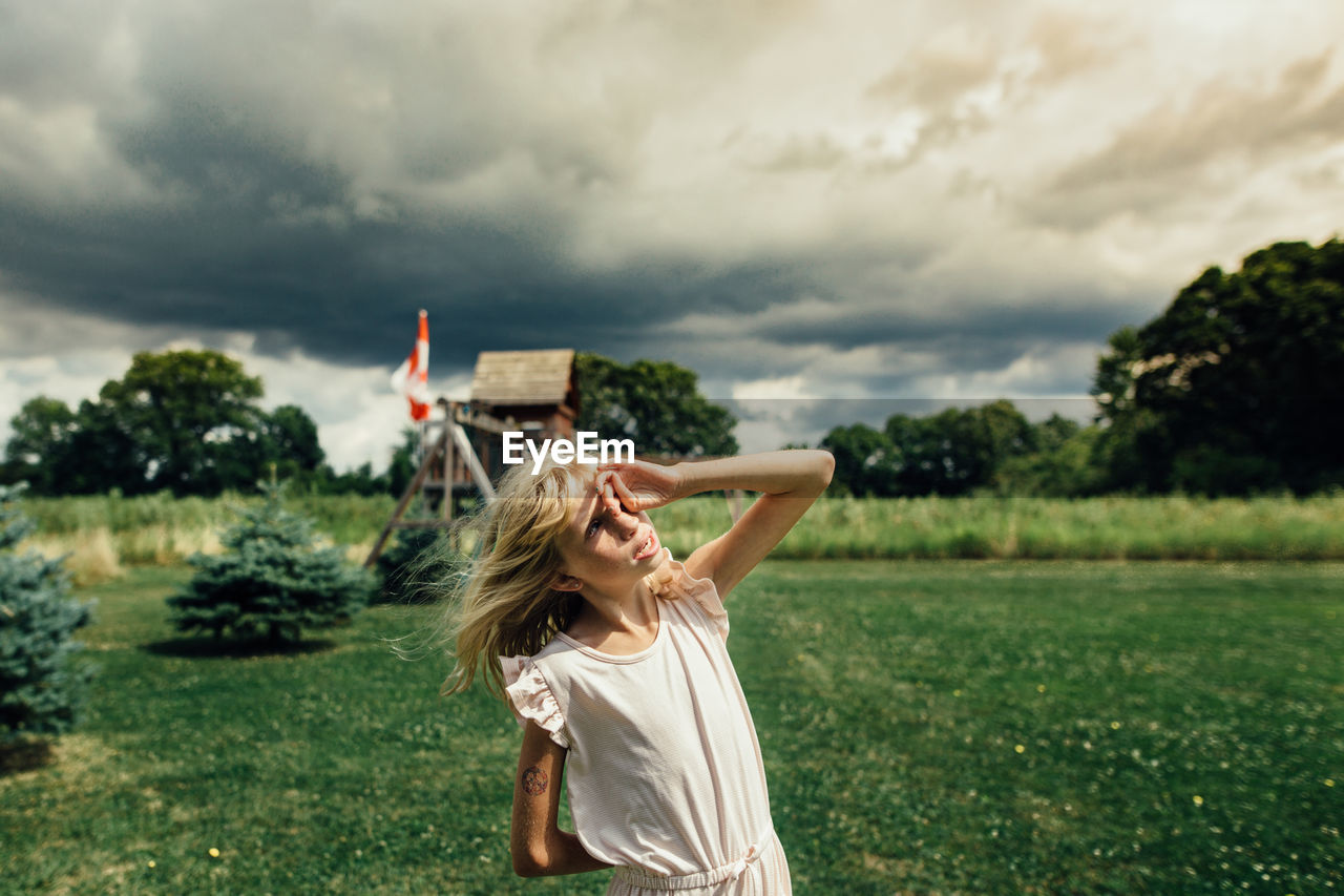 Girl facing the sky on a windy and cloudy day