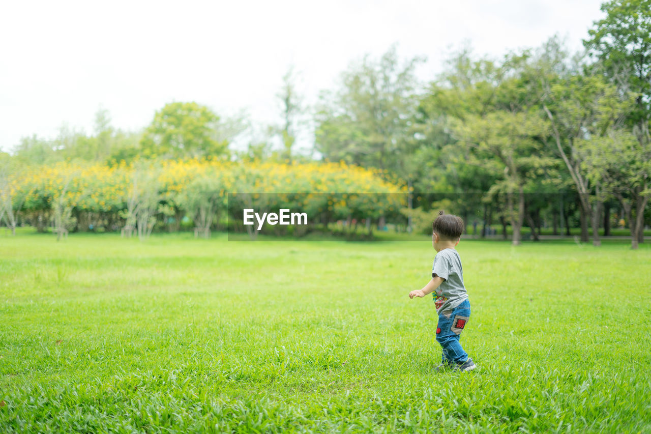 SIDE VIEW OF A BOY PLAYING ON FIELD