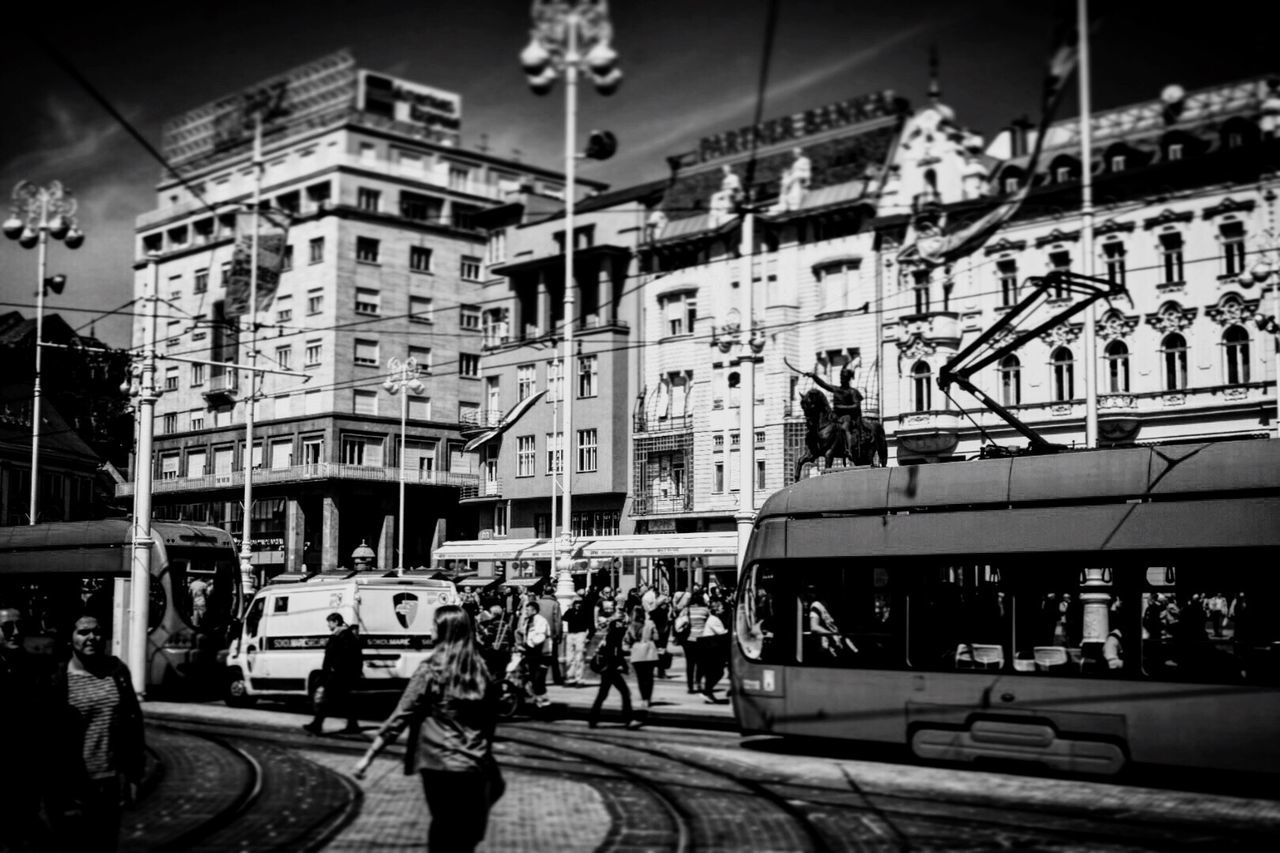 People by cable car on street in city