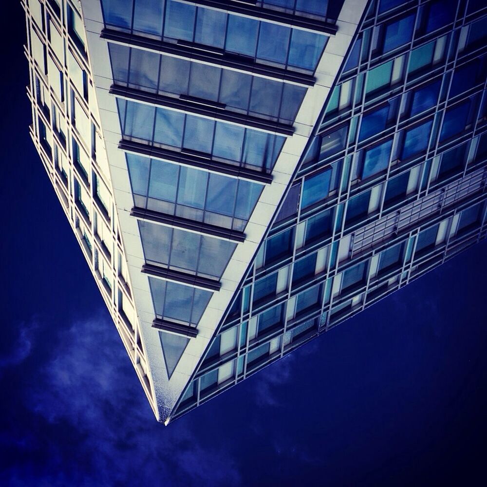 Low angle view of glass office building against blue sky at dusk