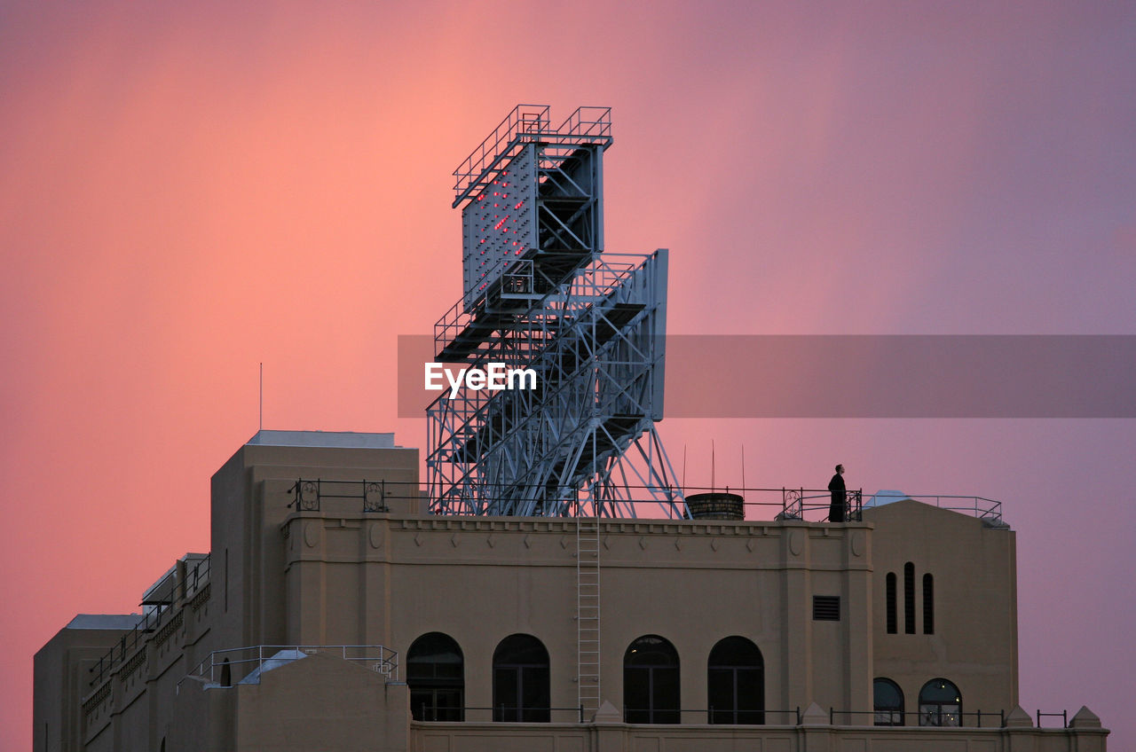 Low angle view of billboard on building against sky during sunset