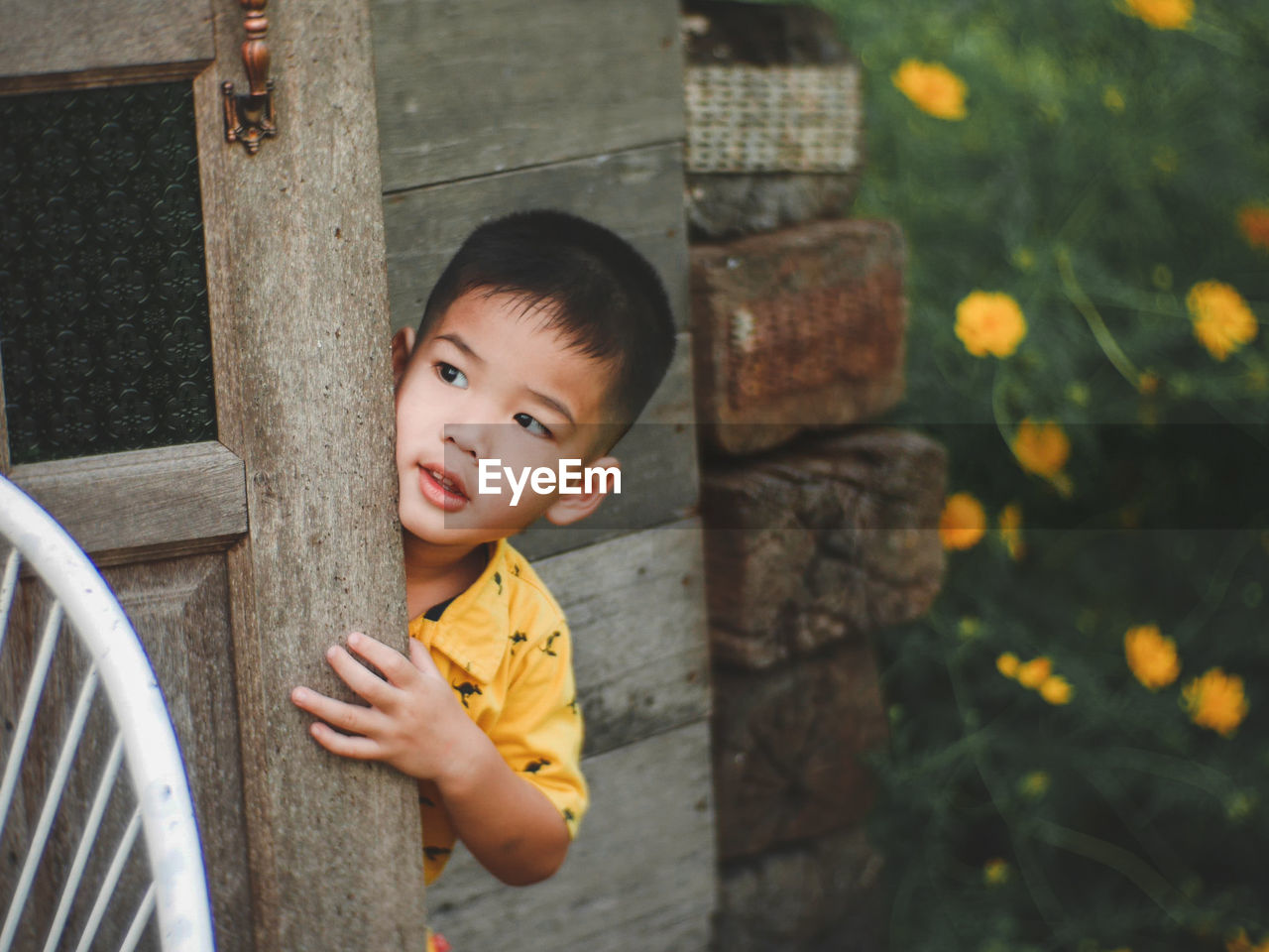 Cute boy standing behind wall