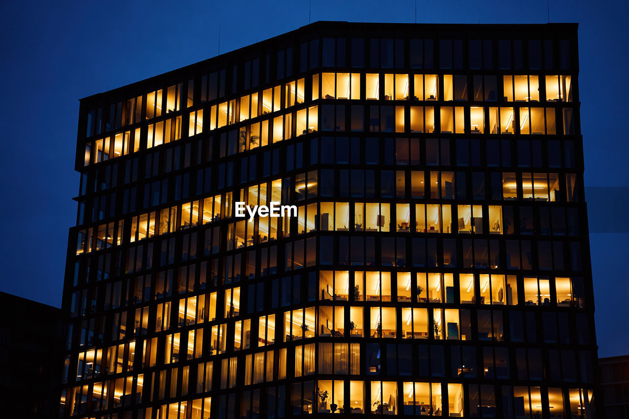 Office building exterior with glowing lights in windows at night city. vienna city downtown 