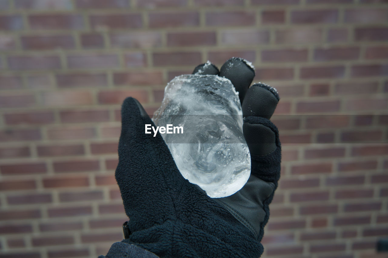 HUMAN HAND HOLDING STONE WALL