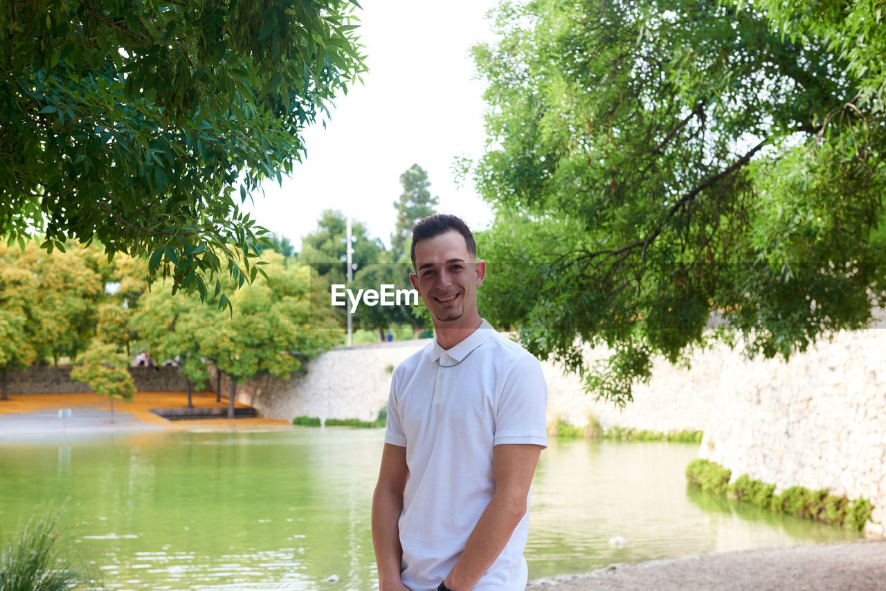 Portrait of young man standing against trees