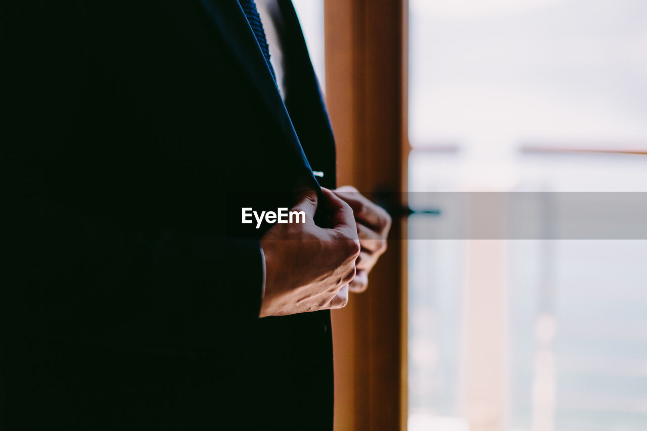 Midsection of businessman adjusting suit