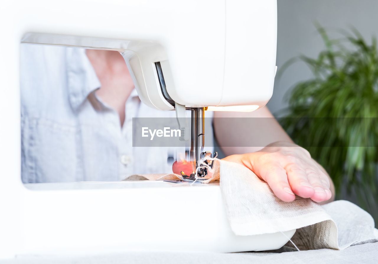 cropped hand of man sewing machine at home