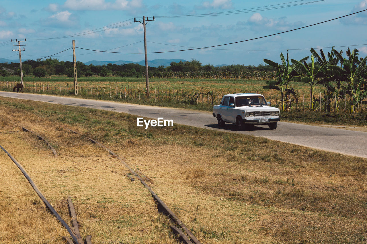 CAR ON ROAD AMIDST FIELD