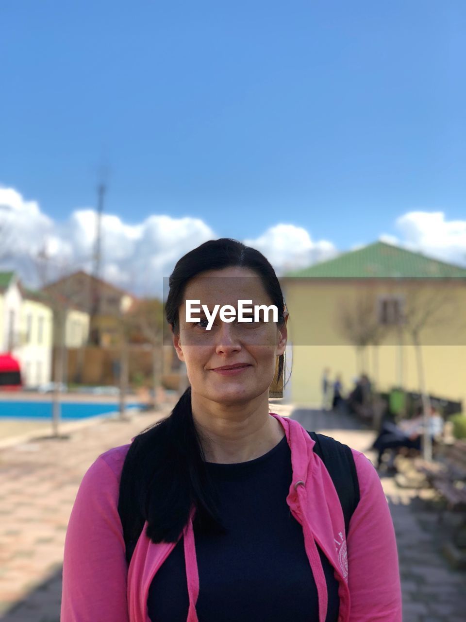 Portrait of woman smiling while standing against blue sky