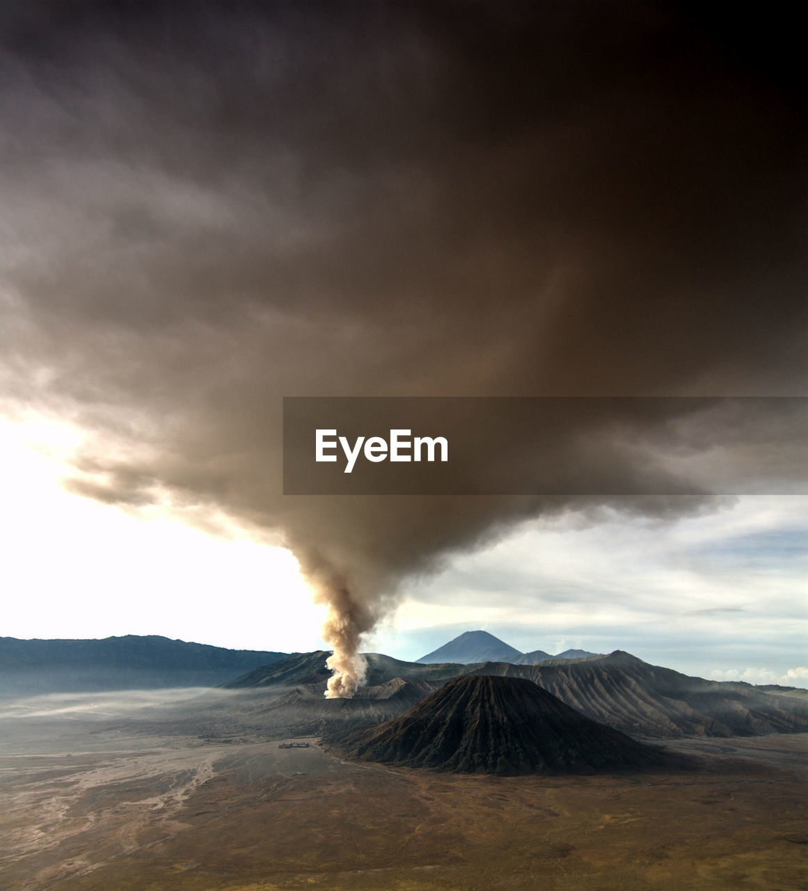 Smoke emitting from bromo volcanic mountain against sky