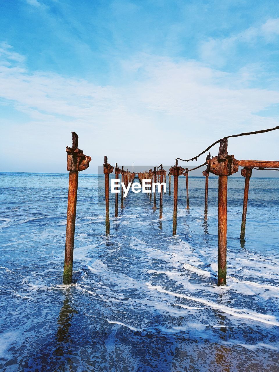 Broken pier over sea against sky