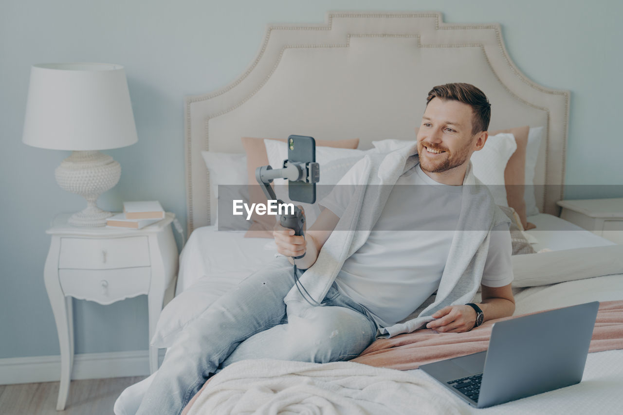 Man using mobile phone while sitting on bed