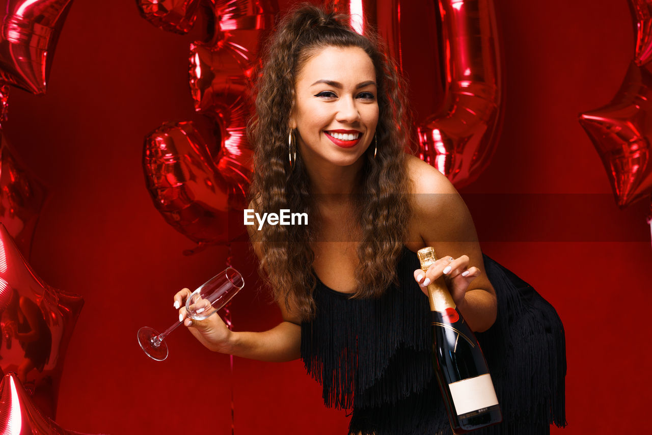 Beautiful woman posing on a red background with balloons