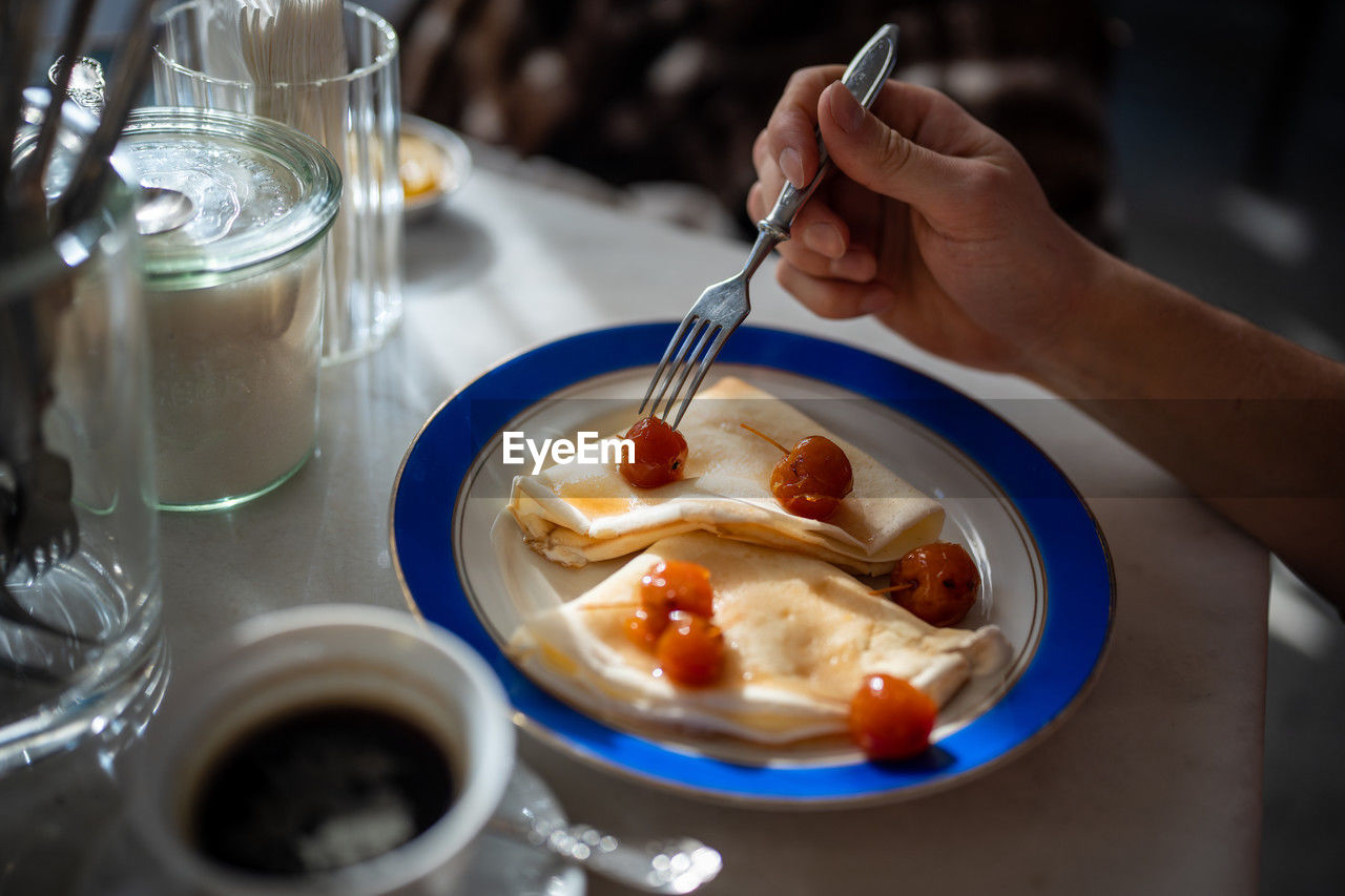 Man having tasty breakfast in restaurant pancakes with jam from apples ranets.