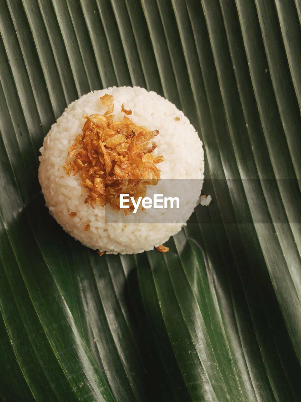 Close-up of rice with fried onion on banana leaf