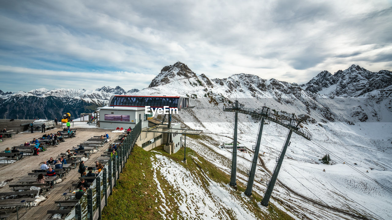 PANORAMIC VIEW OF PEOPLE WALKING ON SNOWCAPPED MOUNTAIN AGAINST SKY