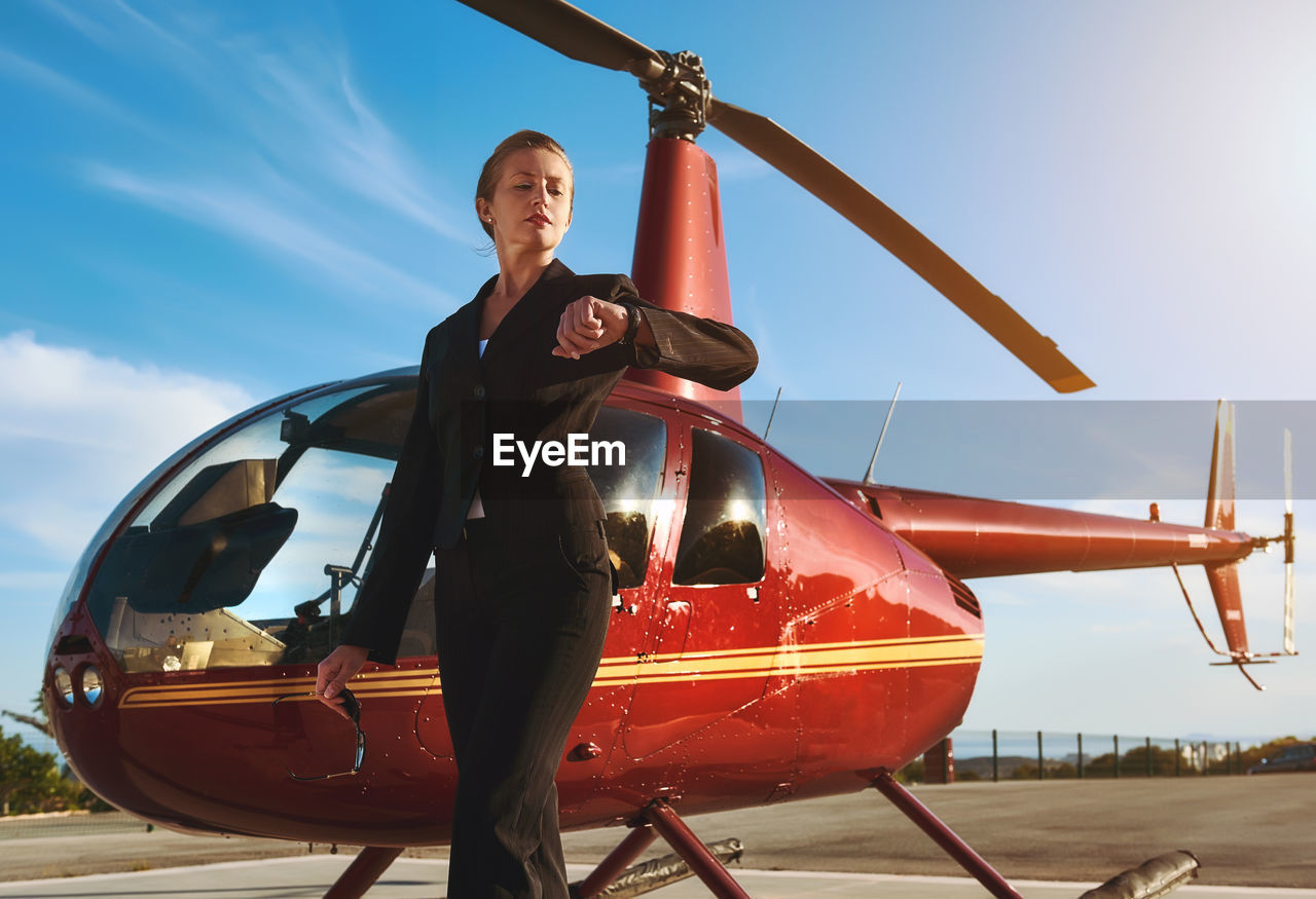 Businesswoman standing by helicopter against sky