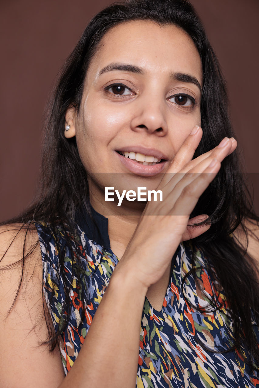 portrait, women, smiling, adult, looking at camera, one person, studio shot, happiness, photo shoot, headshot, long hair, emotion, hairstyle, indoors, teenager, cheerful, human face, young adult, black hair, person, female, portrait photography, colored background, fashion, positive emotion, brown hair, smile, teeth, close-up, skin, front view, enjoyment, brown eyes, lifestyles, human hair, make-up