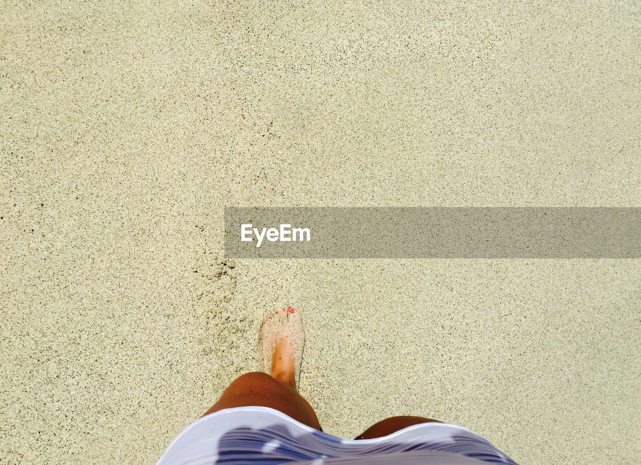 Low section view of woman feet in sand