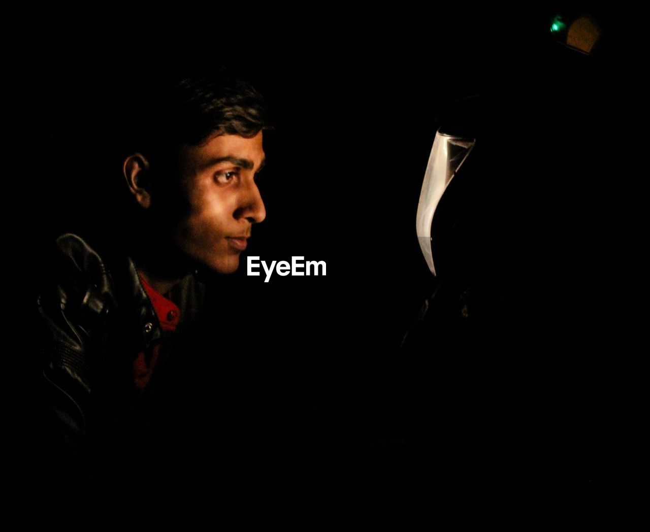 Man looking at illuminated motorcycle headlight in dark