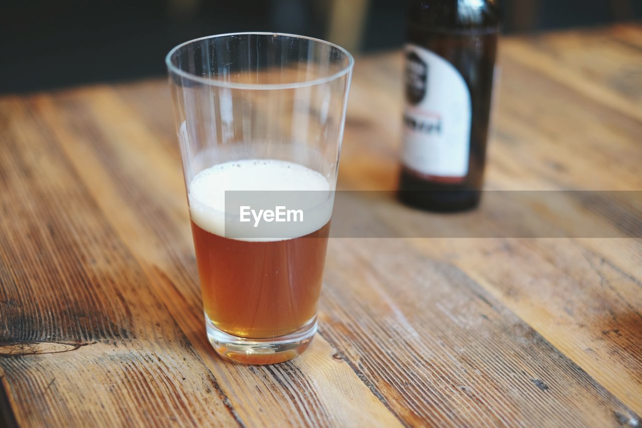 Close-up of beer in glass by bottle on table