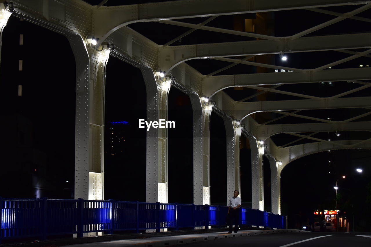 Night lights at a bridge in tokyo if observed, will see a man walking. 