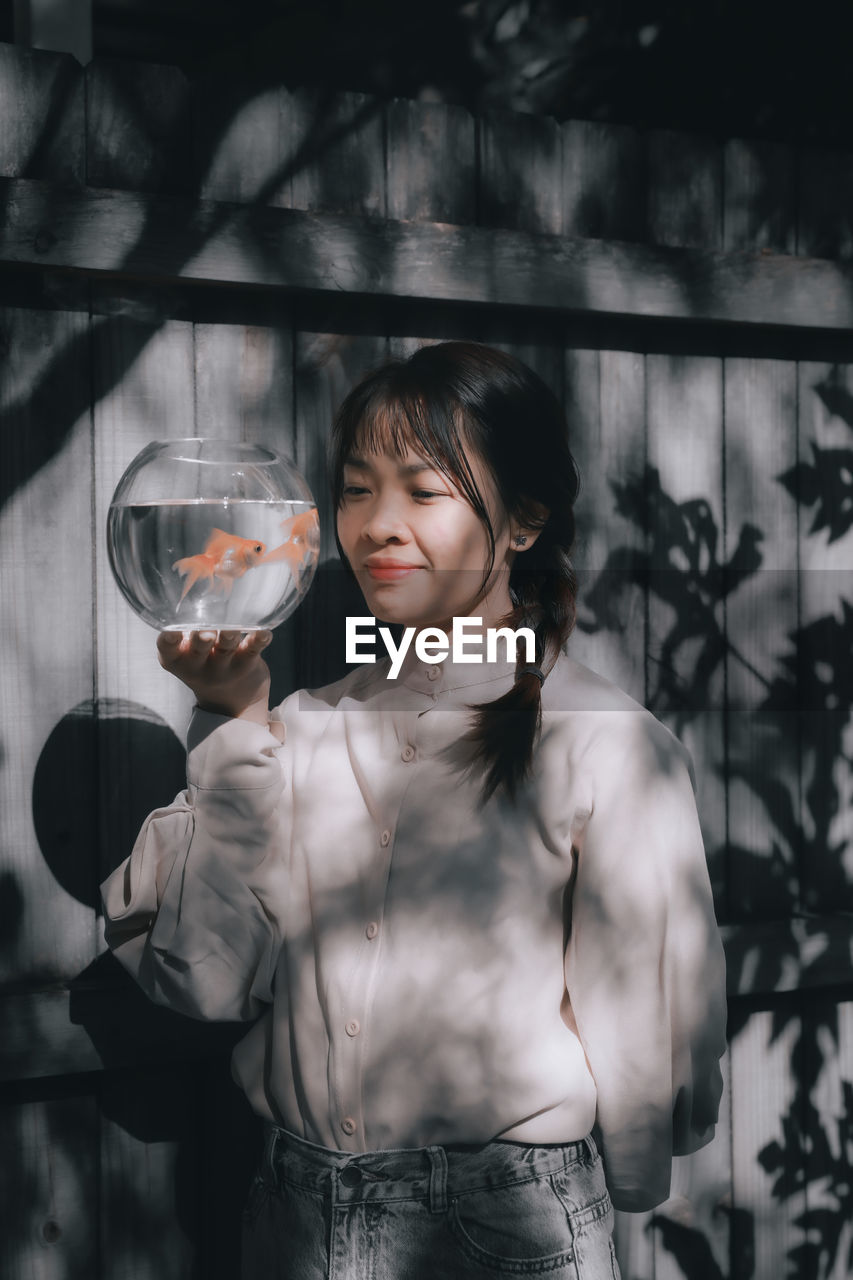 Portrait of young woman holding fishbowl