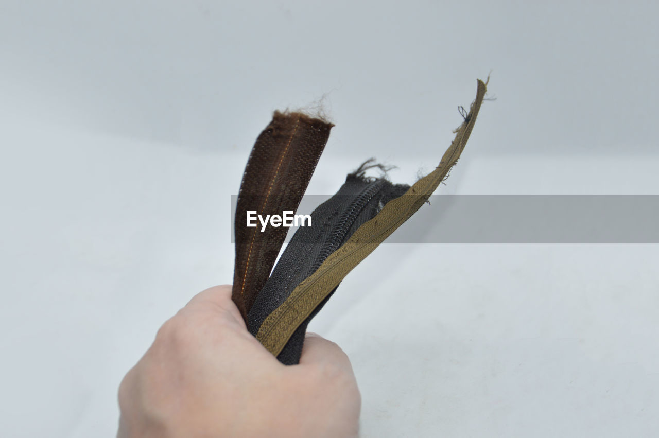 CLOSE-UP OF MAN HOLDING HAND OVER WHITE BACKGROUND