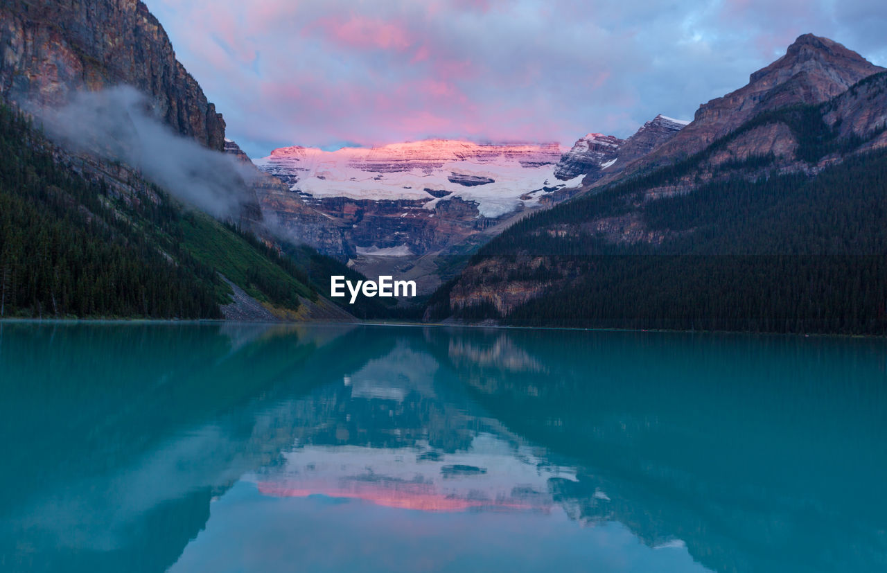 Scenic view of glacial lake and mountains during sunrise at banff national park