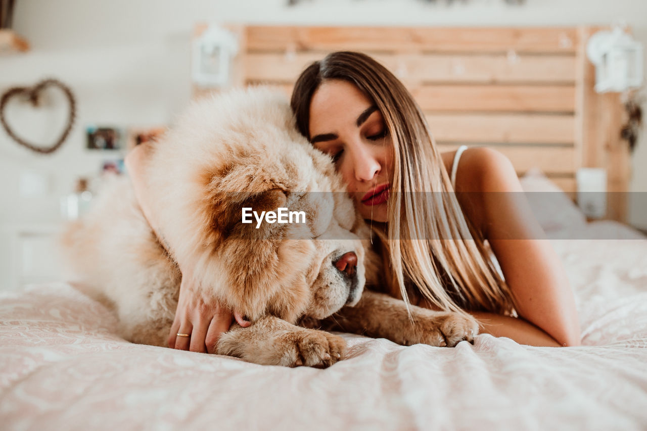 Young woman sleeping with dog on bed at home