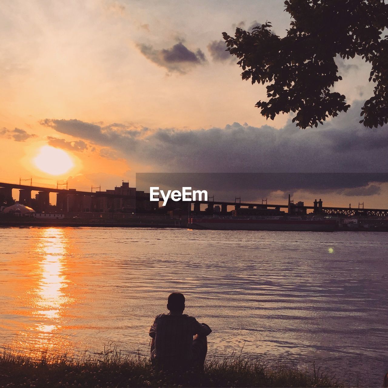 Rear view of man looking at river during sunset