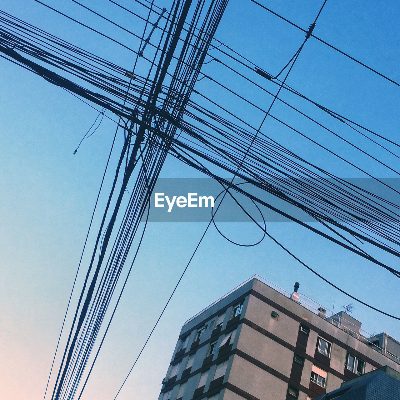 Low angle view of electricity pylon and buildings against sky